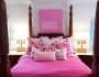 a pink color bed with many cushions and pillows