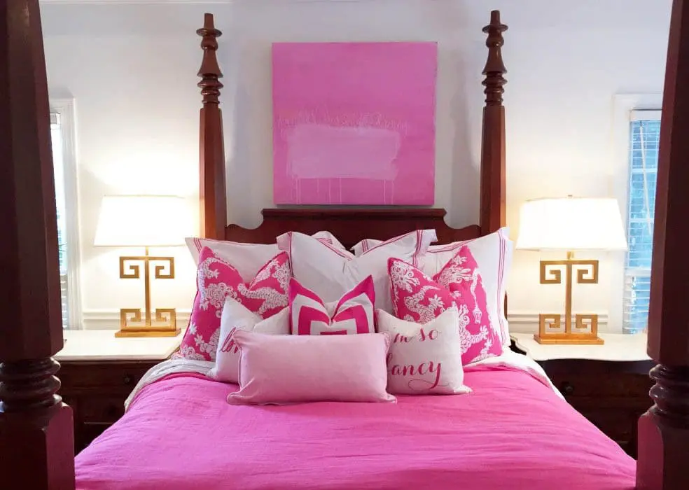 a pink color bed with many cushions and pillows