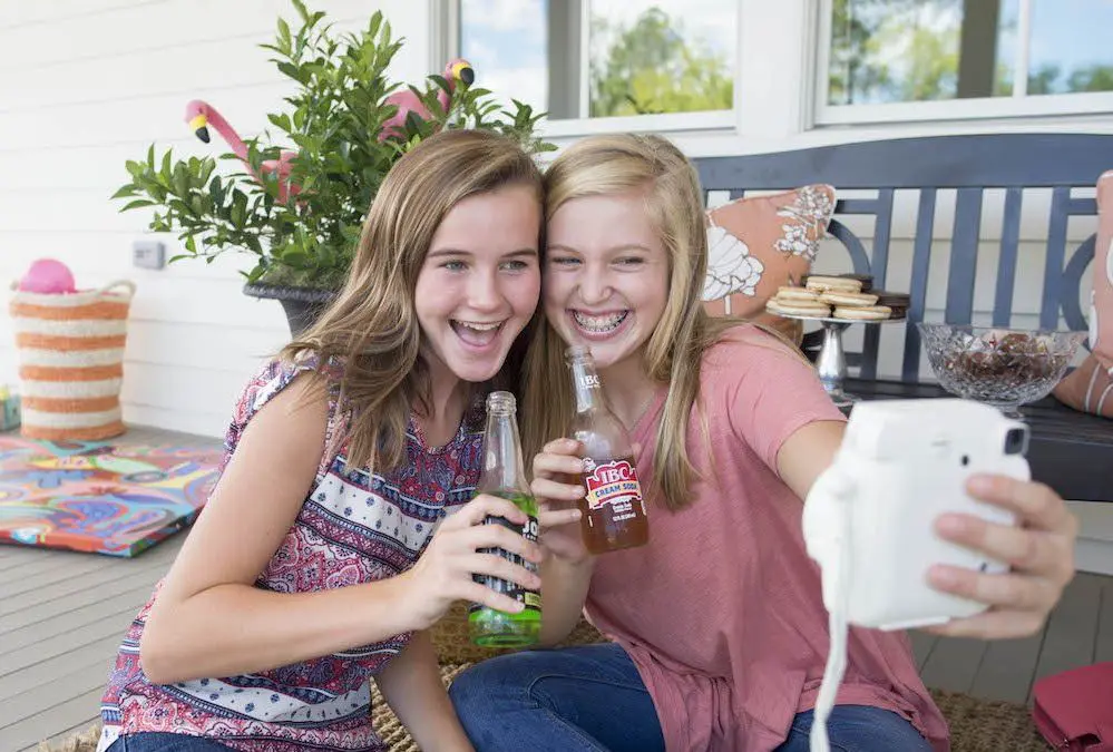 two girls having cold drink and clicking selfie